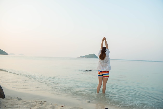 Mujer feliz de pie con los brazos extendidos y disfrutar de la vida en la playa en el mar