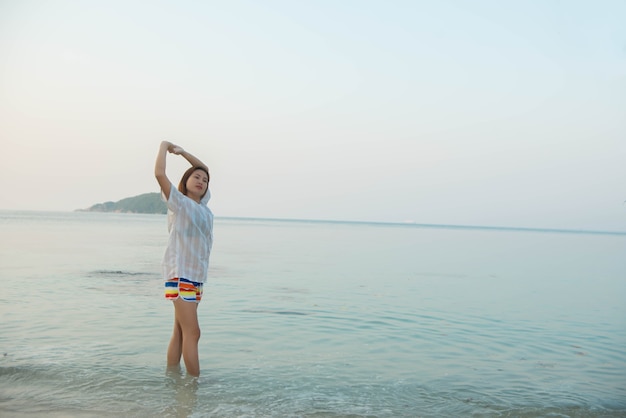 Mujer feliz de pie con los brazos extendidos y disfrutar de la vida en la playa en el mar