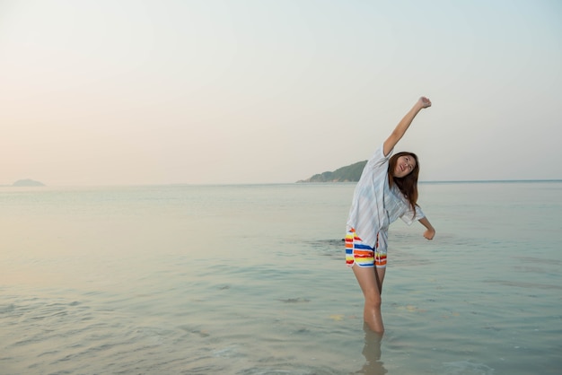 Mujer feliz de pie con los brazos extendidos y disfrutar de la vida en la playa en el mar