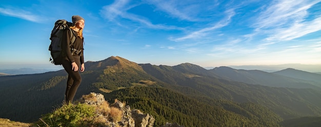 La mujer feliz de pie en la montaña soleada