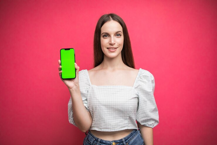 Mujer feliz de pie y sostenga el teléfono inteligente sobre fondo rosa. Pantalla de teléfono de pantalla verde