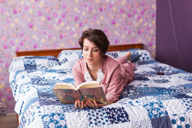 Mujer feliz en pijama y relajarse en casa y leer un libro. Quedarse en casa. Pandemia de cuarentena