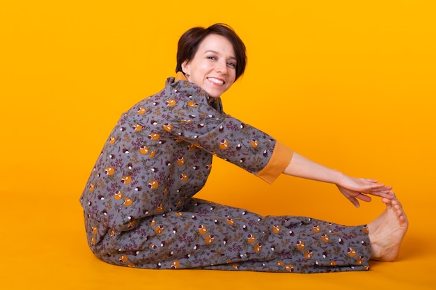 Mujer feliz en pijama sentada en amarillo
