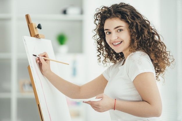 La mujer feliz pintando un cuadro en el caballete