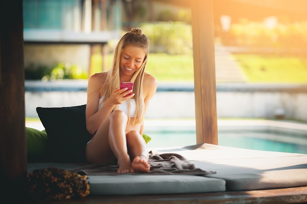 Mujer feliz en la piscina usando el teléfono