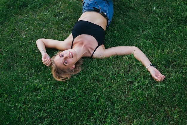 La mujer feliz pone en la hierba en el parque