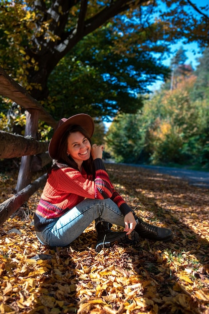 Mujer feliz posando cerca de la valla día soleado de otoño