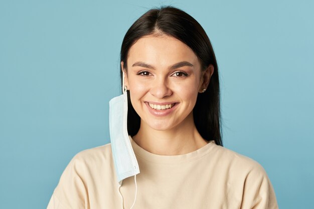 Mujer feliz posando en una máscara protectora desechable de virus