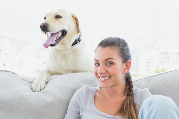 Mujer feliz posando con su labrador amarillo en el sofá