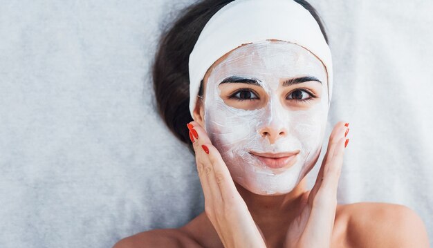 Mujer feliz que se acuesta en el salón de spa y tiene procedimiento de limpieza facial.