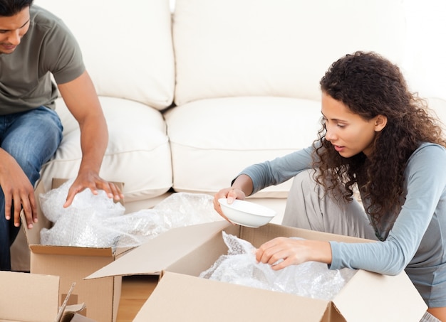 Mujer feliz que embala vidrios con su marido en la sala de estar