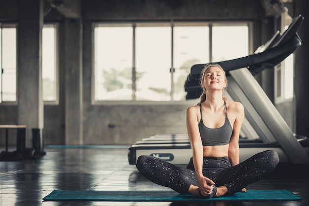 Mujer feliz que estira en yoga mate