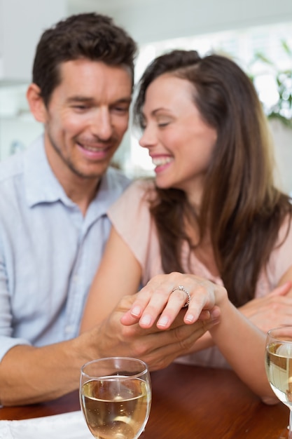 Mujer feliz que muestra el anillo de compromiso además del hombre