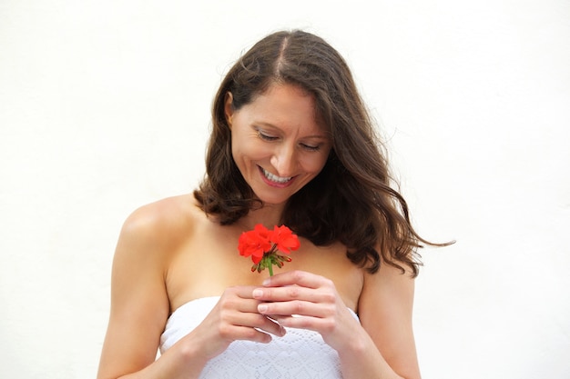 Mujer feliz que sostiene la flor roja