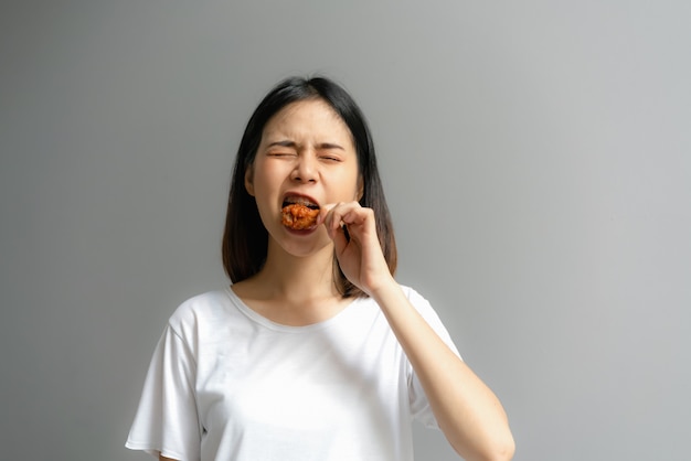 La mujer feliz que sostiene el pollo frito para come.