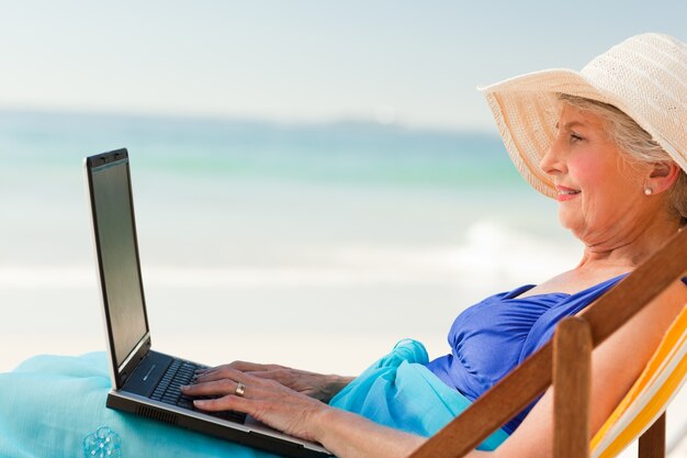 Foto mujer feliz que trabaja en su computadora portátil en la playa