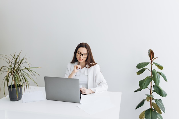 Mujer feliz que usa la computadora portátil en el lugar de trabajo moderno