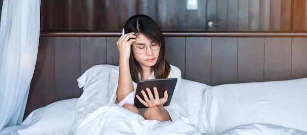 Mujer feliz que usa la tableta para las redes sociales mujer joven viendo películas en la almohadilla de la computadora en la cama en la red de tecnología doméstica compras en línea estilo de vida de comercio electrónico y concepto de comunicación digital