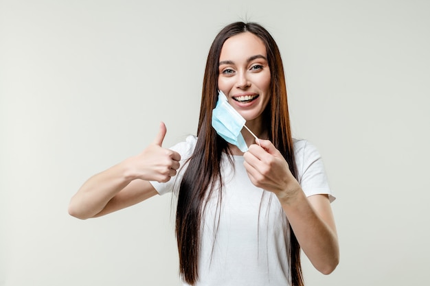 Foto mujer feliz quitándose la máscara con gesto positivo