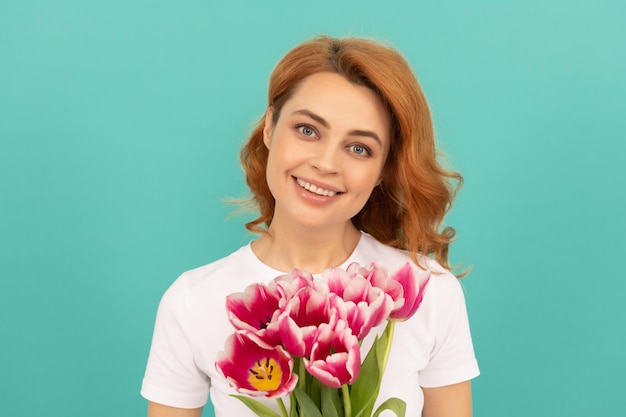 Mujer feliz con ramo de flores de tulipán sobre fondo azul día de la mujer