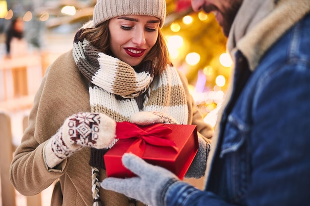 Mujer feliz recibiendo regalo de navidad de novio al aire libre