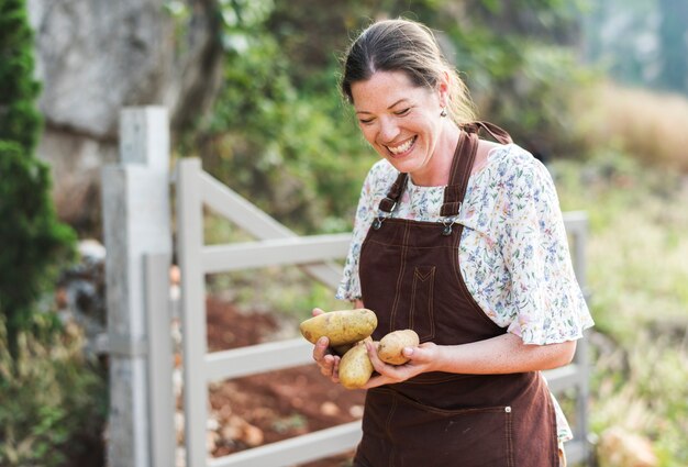 Mujer feliz recogiendo patatas en una granja