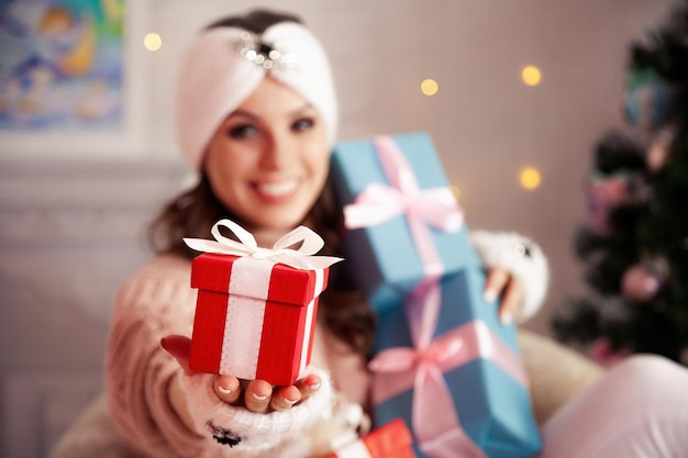 Mujer feliz con regalos frente al árbol de Navidad Mujer elegante en suéter de punto acogedor