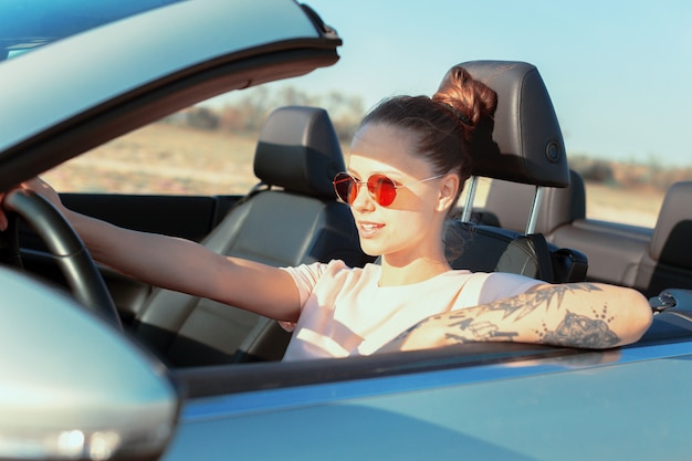 Mujer feliz relajada que viaja en un coche