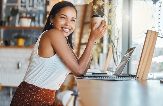 Mujer feliz relajándose en una cafetería con una sonrisa y pensando Mujer disfrutando de un día relajado sola trabajando en una computadora portátil mientras navega por Internet y las redes sociales y tiene una idea de proyecto de inicio