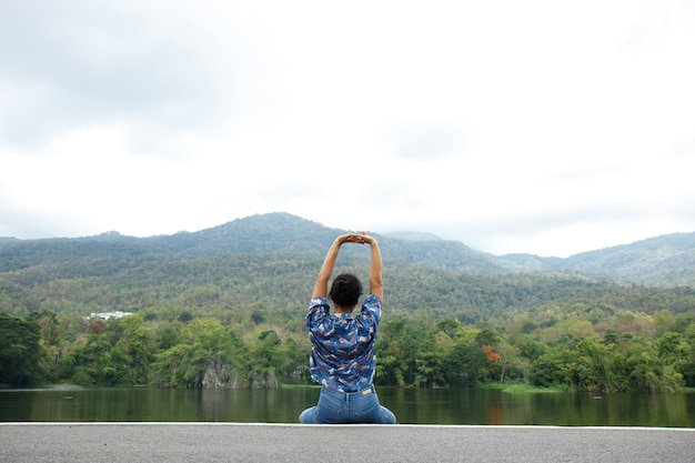 Mujer feliz relajante en el parque, respirando aire fresco al aire libre y disfrutando de la vista del lago.