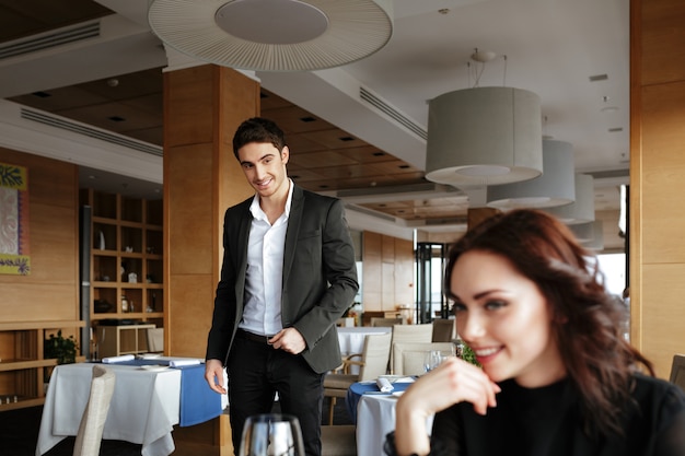 Mujer feliz en restaurante con hombre detrás de ella