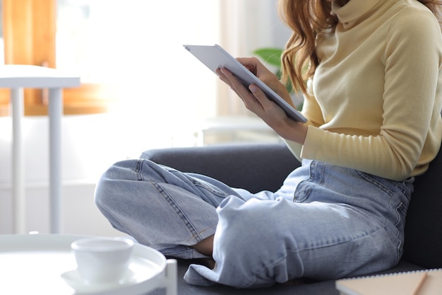 Mujer feliz riendo mientras usa la tableta en casa