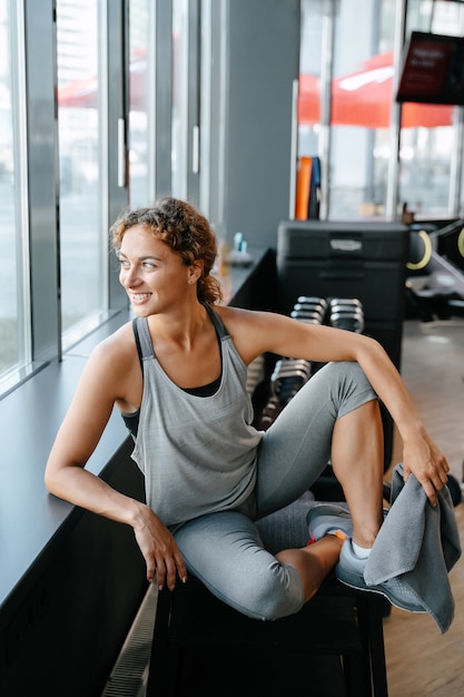 Mujer feliz en ropa deportiva después de un entrenamiento de yoga en el gimnasio está descansando con una toalla concepto de fitness ...