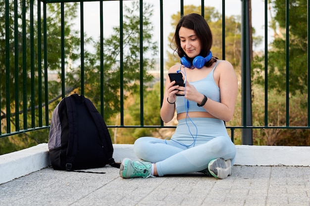 Mujer feliz en ropa deportiva con un teléfono escucha música con auriculares