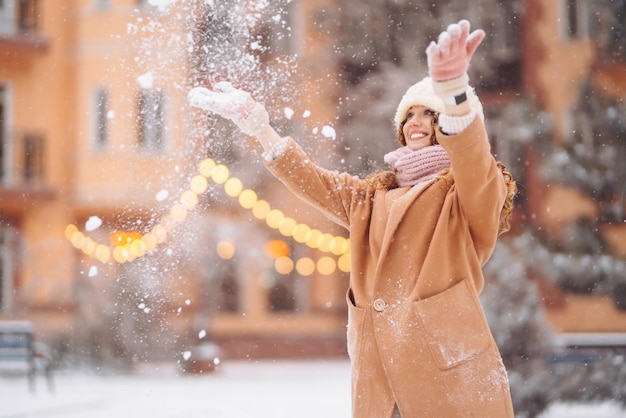 Mujer feliz en ropa de estilo de invierno contra el telón de fondo de luces de guirnaldas Vacaciones de moda de invierno