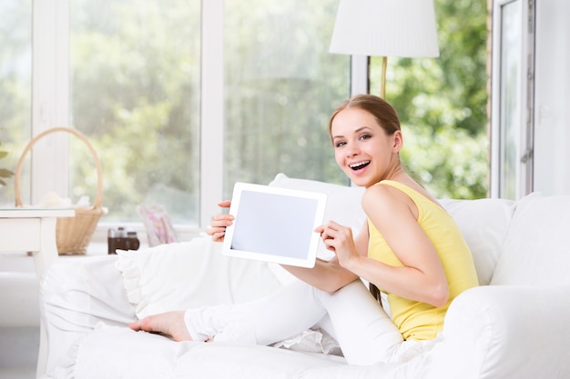 Mujer feliz en la sala de estar mostrando una tableta