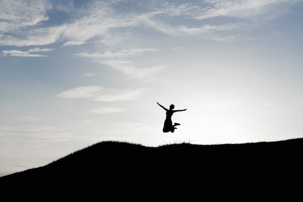 Mujer feliz saltando contra la hermosa puesta de sol