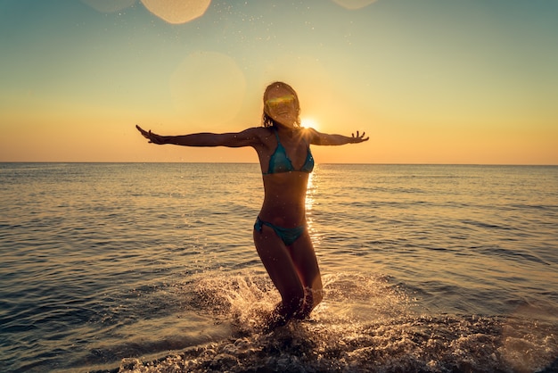 Mujer feliz saltando en el mar Persona divirtiéndose al aire libre vacaciones de verano y concepto de estilo de vida saludable