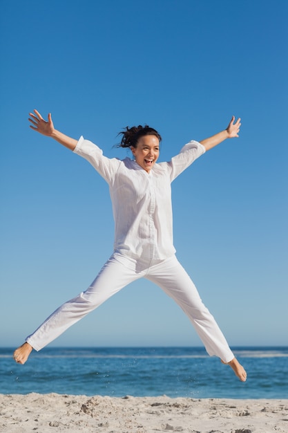 Mujer feliz saltando en la playa