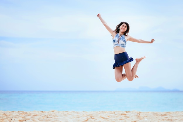 Mujer feliz saltando en la playa