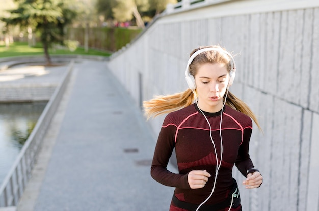 Foto mujer feliz sana corriendo corriendo al aire libre escuchando música