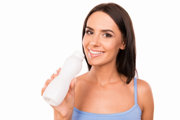 Mujer feliz sana sosteniendo una botella de yogur para beber
