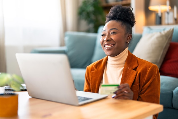 Mujer feliz y satisfecha pagando con tarjeta de crédito mientras compra en línea a través de una computadora portátil