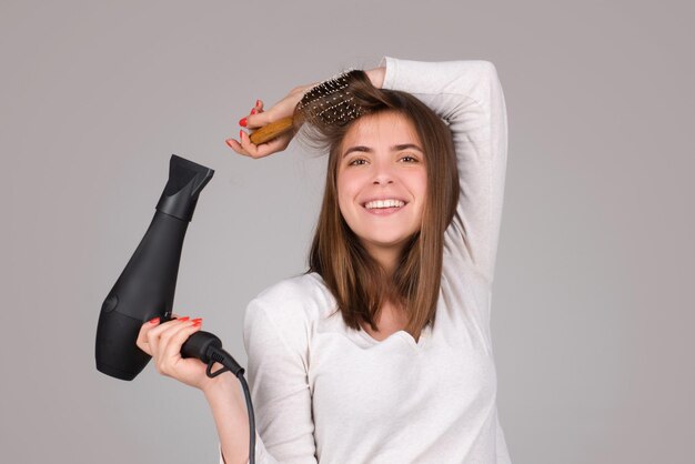 Mujer feliz con secador de pelo hermosa chica con cabello lacio secado de cabello con secador de pelo profesional