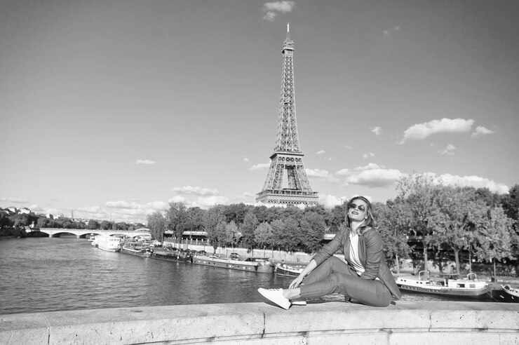 Foto mujer feliz sentada en el río en la torre eiffel en parís, francia sonrisa de mujer con gafas de sol en el cielo azul viajando en vacaciones de verano soñando con parís chica con look de moda y belleza sensual