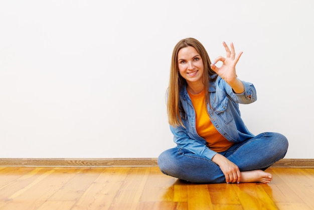 Foto mujer feliz sentada en el suelo mostrando signos de ok