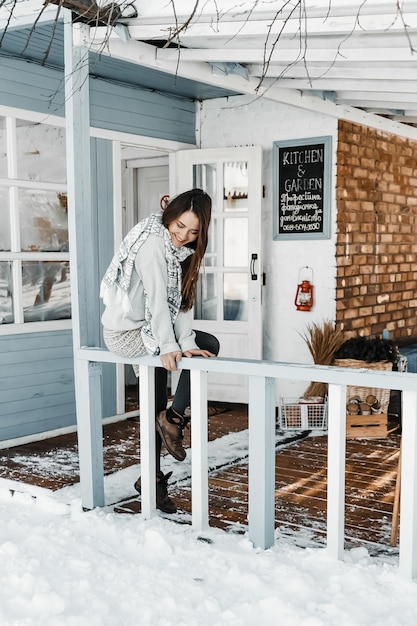 Foto mujer feliz está sentada en la terraza de la casa de la cocina en invierno.