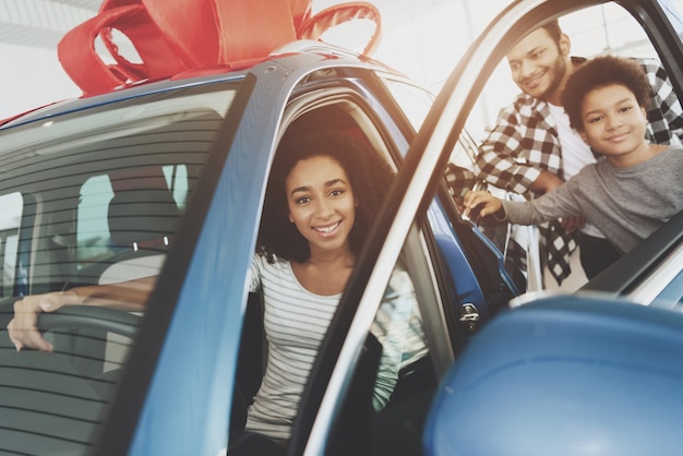 La mujer feliz se sienta en la puerta del coche de regalo se abre.