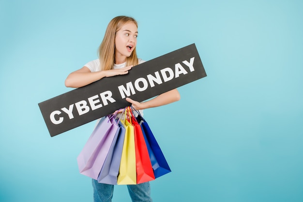 Mujer feliz con signo de lunes cibernético y coloridas bolsas de compras aisladas sobre azul