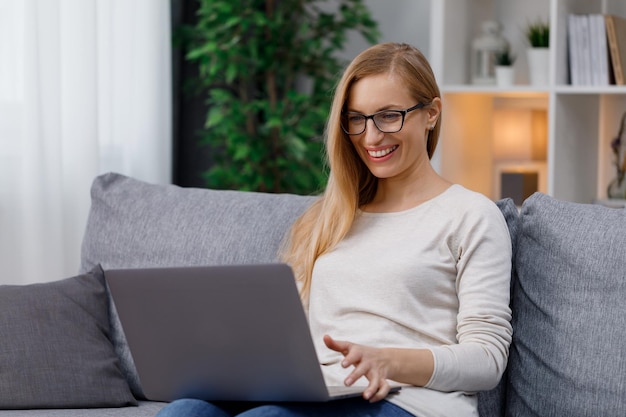 mujer feliz, en, sofá, con, computador portatil